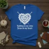 White knitted heart with knitting needles and text "Knitting in my veins Jesus in my heart" on a blue t-shirt