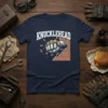 Navy blue t-shirt with "KNUCKLEHEAD" text above a golden fist breaking through a brick wall graphic