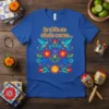 Blue t-shirt with yellow text "la vida es chula como..." and colorful Mexican folk art floral design with hummingbirds and