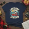 Lake Day Legend fishing t-shirt featuring a cartoon badger captain on a boat with fishing rods and a sunset background
