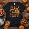 Leaf Blower T-Shirt design with an acorn character using a leaf blower, surrounded by fall leaves and text "Leaf Blower"