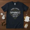 Quote "LEAVE A LITTLE SPARKLE WHEREVER You Go" in decorative gold and white typography on a navy blue t-shirt
