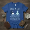 Blue t-shirt with "left it in the waters" and Romans 6:4 scripture, depicting baptism with two figures in water