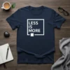 Minimalist "Less Is More" quote t-shirt in white text within a square box on a navy shirt