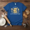 Blue t-shirt with "Let's Dough This!" text and baking graphics including a stand mixer, rolling pin, and utensils