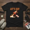 Black t-shirt with "LET'S GO!" text and an orange rocket launching with a checkered flag
