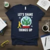 Christmas T-Shirt with "LET'S SHAKE THINGS UP" text and a snow globe graphic featuring pine trees