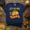 Let's Taco Bout Graduation T-Shirt featuring a cartoon taco wearing a graduation cap and holding a diploma. The text "LET'S