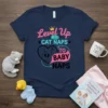 Level Up Cat Naps to Baby Naps t-shirt with crown graphic and sleeping cat illustration. Features text in pink and
