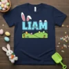 Personalized Liam Easter Bunny T-Shirt with name in blue block letters and bunny ears, featuring Easter eggs and carrots on