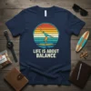 T-shirt with "Life Is About Balance" text and a person doing a handstand on a surfboard at sunset