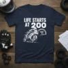 White text "LIFE STARTS AT 200" above a graphic of a motorcycle racer and speedometer on a navy blue t-shirt