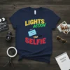 Lights Action Selfie text with smiling phone graphic on navy t-shirt, photography theme