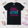 Black t-shirt with "little ASTORIA princess" text in pink and blue, featuring a golden crown graphic