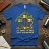 Blue t-shirt with "LIVE AMONG THE TREES - EXPLORE YOUR IMAGINATION" text and a charming illustration of treehouses with foxes