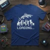 Blue t-shirt with "LOADING..." text in white pixel art, above a cityscape with a flying retro spaceship design