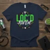 Navy blue t-shirt with "LOC'D nurse" design in green and white, featuring medical symbols like caduceus and syringes