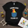 Black t-shirt with white text "LOOKING GOOD! FEELING FLY!" and a cartoon parrot in a blue pocket