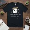 Black t-shirt with white text that reads "Looks serious but actually nice" above a white square graphic with an angry