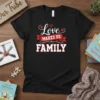 Black t-shirt with white and red text "Love Makes Us FAMILY" design, featuring hearts and a banner