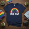 Navy blue t-shirt with white text "LOVE WINS" below a colorful rainbow and two hands forming a heart