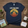 Navy t-shirt with "LOVE YOU MOM" text above a sunset circle featuring two green dinosaurs, perfect for Mother's Day