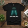 Black t-shirt with a teal and white graphic of lungs forming a tree, with the text "LOVE YOUR LUNGS" below