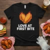 Black t-shirt with "Love At First Bite" text and a heart graphic made of chicken wings on fire, primary keyword