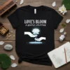 Love's Bloom A Gentle Uplifting text with a glowing lotus flower held by hands on a black t-shirt