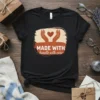 Black t-shirt with "MADE WITH handle with care" text and a heart graphic between two hands