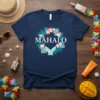 Navy blue t-shirt with the word MAHALO in white, surrounded by a tropical floral and leaf wreath with two surfboards