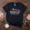 Makeup Artist text design with makeup brush graphic and sparkling accents on a navy t-shirt
