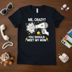 Me, Crazy? You Should Meet My Mom quote on a black t-shirt with a hairdryer graphic, stars, and lightning bolts
