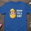 Meow I'm A Cat text with a cute kitten hatching from a yellow egg graphic on a blue t-shirt