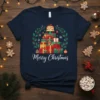Merry Christmas text with a stack of festive gift boxes and a holly wreath design on a navy t-shirt