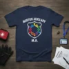 Navy blue t-shirt with "MERTON AUXILIARY M.A." and a shield logo featuring colorful figures representing community support