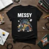 Black t-shirt with the word MESSY in bold white letters above a chaotic illustration of a laundry basket overflowing with