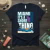 Miami It's A Shore Thing text design with a beach sunset graphic on a navy t-shirt