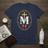 Navy blue t-shirt featuring the Miraculous Medal emblem with golden cross, M, flaming hearts, and stars