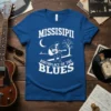 Blue t-shirt with white text "MISSISIPII BIRTHPLACE OF THE BLUES" and a graphic of a guitarist under a moon
