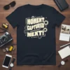 Moment Captured Next! text design with camera aperture graphics on a black t-shirt