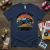 Monster Truck Mom t-shirt design featuring a blue and white monster truck climbing a dirt mound with mountains and a