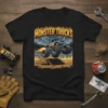 Black t-shirt featuring a dynamic MONSTER TRUCKS graphic with a blue monster truck jumping over a ramp with flames and