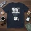 Moody In The Morning t-shirt with a grumpy coffee cup graphic and white text, featuring a small alarm clock and