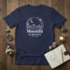 Moonlit Acreage Est 2024 T-Shirt featuring a rustic barn, fields, and floral wreath under a crescent moon