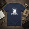 More Will Be Revaled quote on a navy blue t-shirt with a scroll graphic and question marks