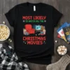 Black t-shirt with "Most Likely To Watch All The Christmas Movies" text and graphic of armchair, TV, and popcorn