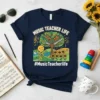 Navy t-shirt with "Music Teacher Life" text and a musical tree graphic featuring instruments and sunflowers. Includes #MusicTeacherlife hashtag