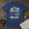 My Animals Love Me t-shirt design featuring white text and illustrations of a dog, cat, parrot, guinea pig, and rabbit