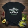 Black t-shirt with white text "MY BIRTHSTONE IS A MOLCAJETE" and a green outline of a molcajete and diamond graphic